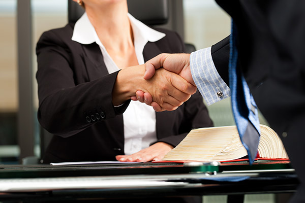 A woman in a business suit shaking a man's hand across a table