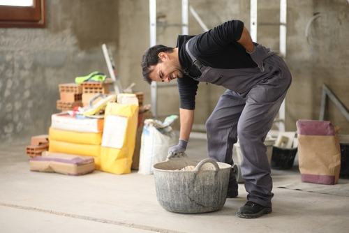 A man grabbing his back in pain as he bends down to pick up a basket