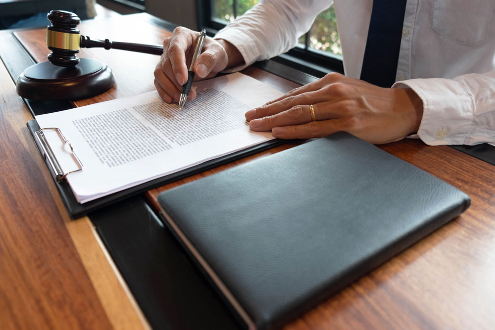 A man reading through a legal document with a judge's gavel next to him